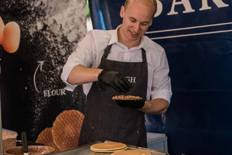 Gerbrand, eigenaar van Dough, werkt in de kraam een stroopwafel af met stukjes topping