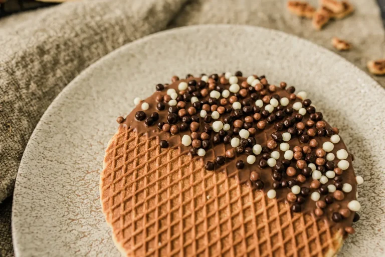 Stroopwafel half gedoopt in chocolade met chocoladeballetjes